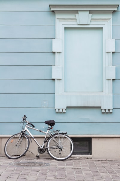 灰色城市自行车停放在墙上的人行道上